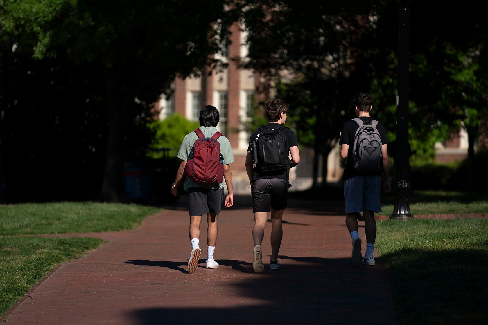 Three students walk on a college campus.